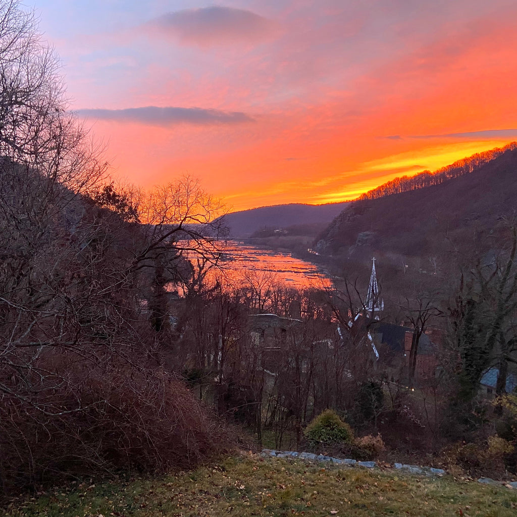 Village landscape with a vibrant sunset over a river