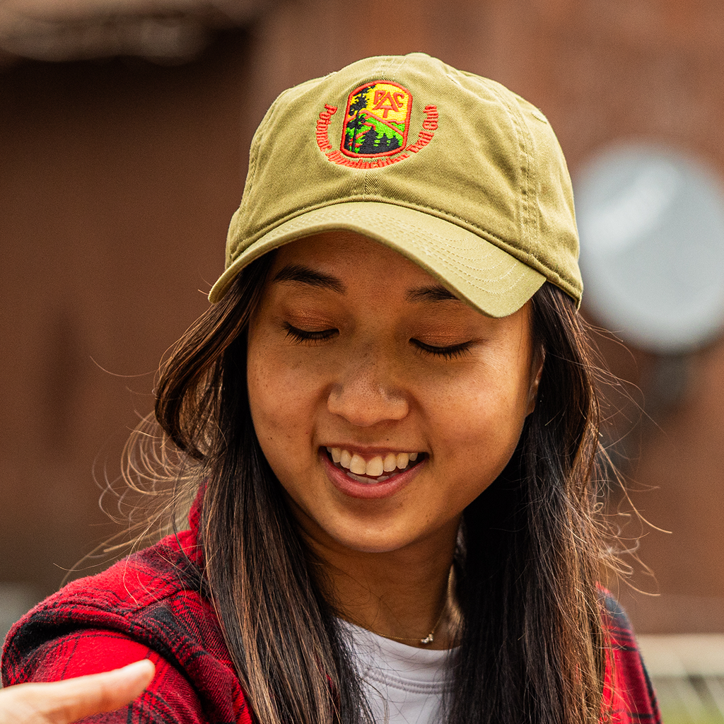Person looking down and wearing a tan PATC baseball cap